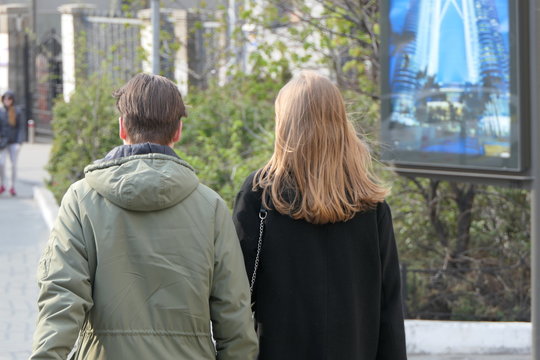 Young Couple Walking On The Street, View Fron Behind