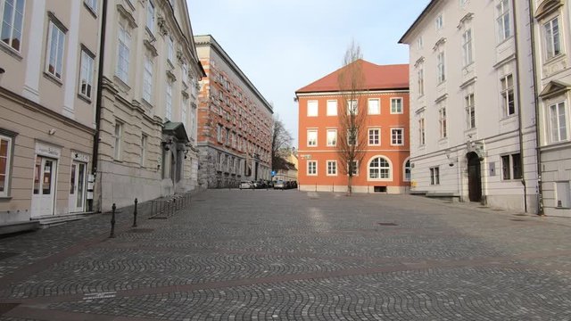 Bike ride through Ljubljana city downtown streets and square on workday, Slovenia. Coronavirus COVID 19 quarantine pandemic lockdown restrictions. Forward dolly moving, wide shot