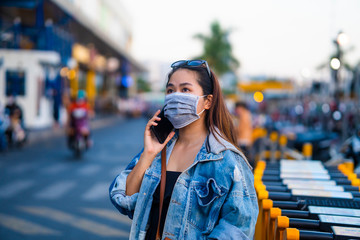 Young woman wearing surgical mask on street while using phone. Concept, diseases, viruses, allergies, air pollution.  Prevention of bacterial infection Corona virus or Covid 19 in the air 