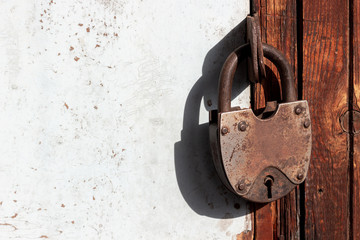 Rusty closed padlock on old door. Private property or secrets concept background. Selective focus