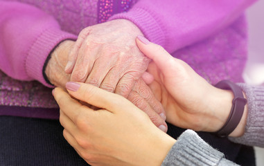 Hands of young adult and senior women. Senior and young holding hands outside. Elderly concept