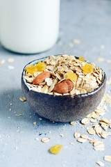 Home granola in a bowl. Selective focus. Healthy vegan snack. Granoll morning breakfast with almonds, raisins, dried cranberries on a blue (gray) background. Healthy eating concept