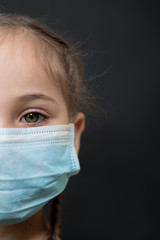 Half face girl with red eyes and a medical mask on a black background, copy space. Concept of people who are isolated in a coronavirus quarantine.