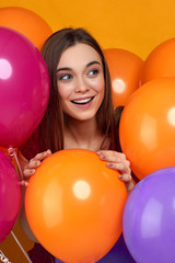 Fototapeta na wymiar Smiling caucasian girl posing with bright color air balloons on yellow background. Beautiful happy young woman on a birthday holiday. close-up