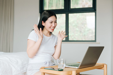 Young Asian girl using laptop in bed