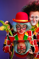 two clowns a man and a woman with bright makeup in colored costumes say they look at their reflection in the mirror. 