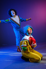 Fototapeta premium Two clowns a man and a woman with makeup in bright colored tracksuits in the style of the 80s.