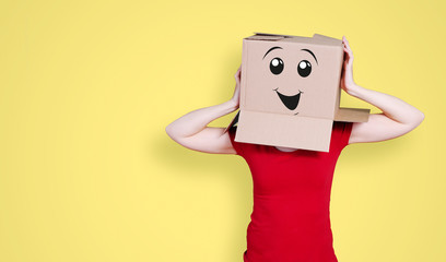 Person with cardboard box on its head and a happy face expression holding its head on yellow background