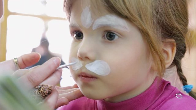 Artist painting on face of small girl