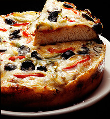 Pizza slice dough very thick with olives and red pepper and delicious melted parmesan cheese