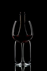 A bottle of wine and a crystal wine glass on a black background.