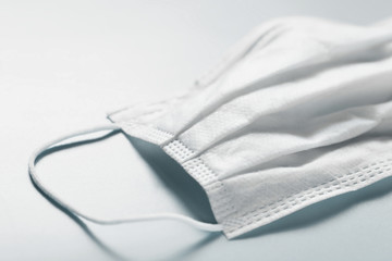White disposable medical face mask on gray background. Single used doctor mask on table. Corona...
