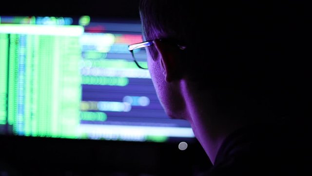 Male programmer with glasses working late at night
