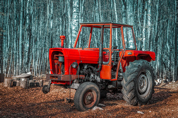 Close up view of one old red tractor abandoned in the forest. Concept for industrial pollution of nature.
