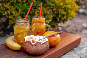 Two summer sour-sweet cups of lemonade with citrus lobules of lemons, oranges, grapefruits on the table under sunshine