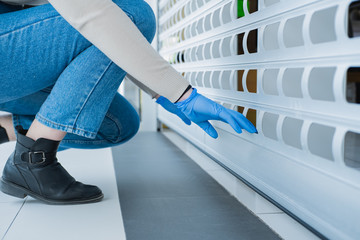 Woman in hand gloves closes the roller blinds of a shop. Lock down, close down of retailing...