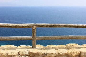 wooden low fence with a stone base on a background of blue sea and sky