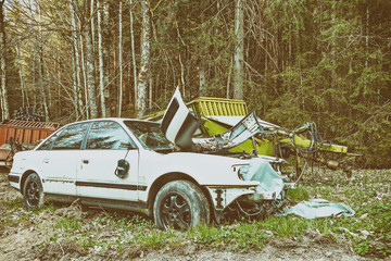 Abandoned car wreck and hay cart in the woods. Retro style
