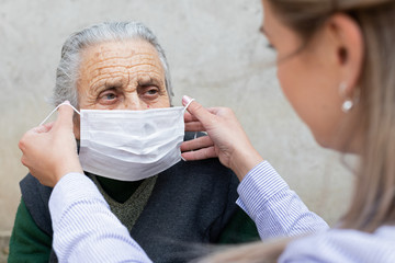 Nurse putting on mask on elderly woman