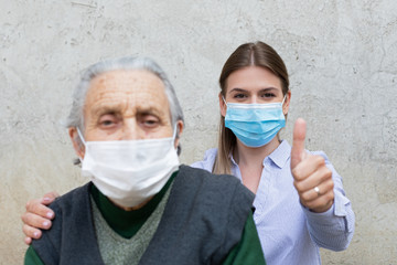 Caregiver with elderly ill woman showing thumbs up
