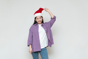 A young asian woman in a Christmas hat stands in front of the white wall
