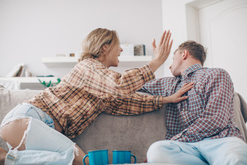 Unhappy young millennial married couple sitting on couch in living room at home and quarrelling. Husband arguing emotionally talking frustrated wife looking away. Break up and misunderstanding concept