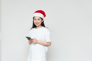 A young asian woman in a Christmas hat stands in front of the white wall