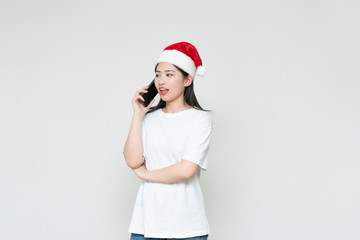 A young asian woman in a Christmas hat stands in front of the white wall