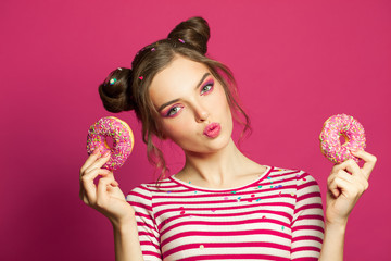 Cute woman holding donut on vivid pink background, diet concept