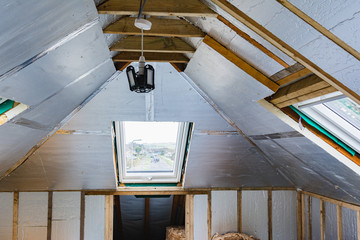 Loft conversion, unfinished project, silver insulation, roof windows, wood structure of the walls,...