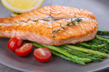 Grilled salmon steak butterfly and asparagus on a gray plate