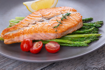 Grilled salmon steak butterfly and asparagus on a gray plate