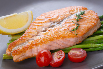 Grilled salmon steak butterfly and asparagus on a gray plate