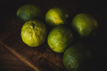 Green lime fruits lying on a wooden kitchen surface.
