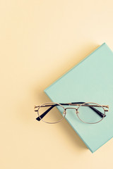 Stylish eyeglasses over pastel  background. Optical store, glasses selection, eye test, vision examination at optician, fashion accessories concept. Top view