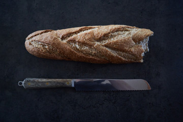 Bread on a dark table in the kitchen with a knife