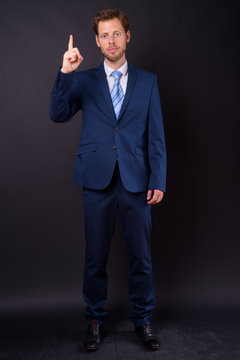 Full body shot of bearded businessman in suit pointing up