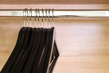 Close-up many empty black clothing racks hanging on coathanger in closet with copy space