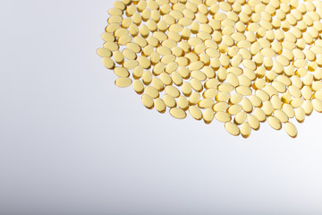 Softgels of Omega-3 on light background with copy space. Fish oil on a white background. Yellow capsules with medicine. Medical medicament of polyunsaturated fatty acids. Macro top view