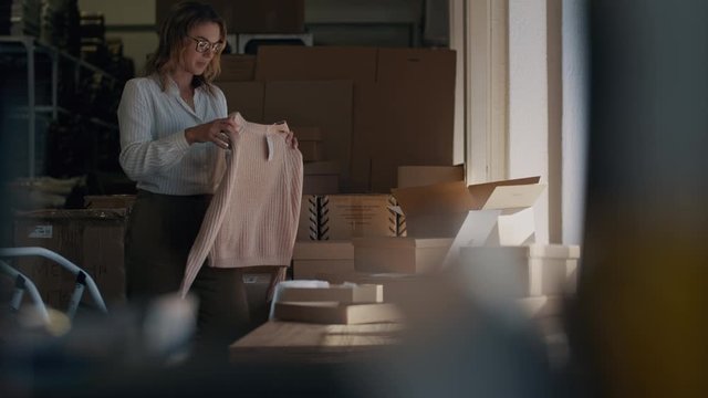 Woman checking a laptop for new order and packing the product for delivering to the customer. Online business owner working at the office, preparing the order
