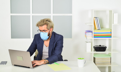 Self isolation top response tactic for managing outbreak of COVID 19. Home office. Man wear medical mask work with laptop. Avoid contact with other people. Stay home. Working from home. Online