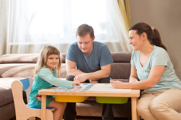 Fototapeta premium Rodzina tata, mama i córeczka grają razem w gry planszowe w domu. Kwarantanna. pojęcie zdrowia. Korona wirus. Rodzina zabawy w domu. koncepcja pozostania w domu