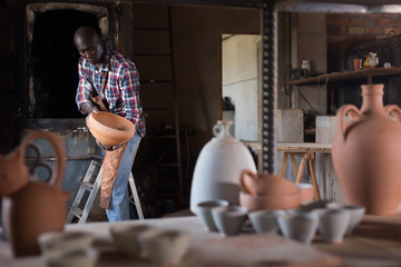 Fototapeta na wymiar Potter checking quality of ceramic objects
