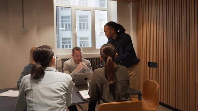 Young businessman talking with a diverse group of colleagues during a staff meeting in an office boardroom
