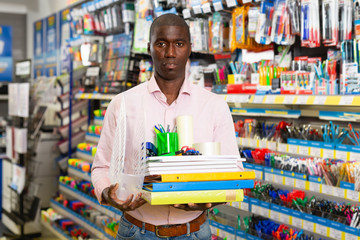 Glad buyer holding stack with office supplies