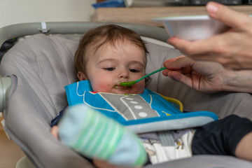 mother feeding her baby boy with a spoon