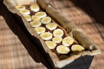 Baking form filled with banana bread dough. Cutted banana on top.