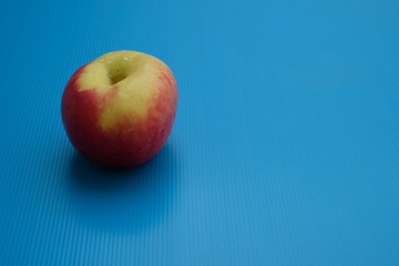 Half red and yellow apple on blue background