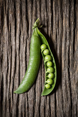 open and isolated pea pod on a rustic wooden base in zenithal view