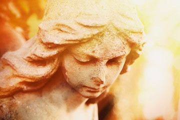 Fragment of ancient stone statue of very beautiful angel in sunlight.